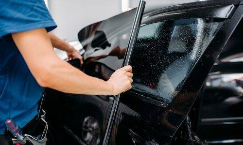 Male specialist applying car tinting film, installation process, tinted auto glass installing procedure